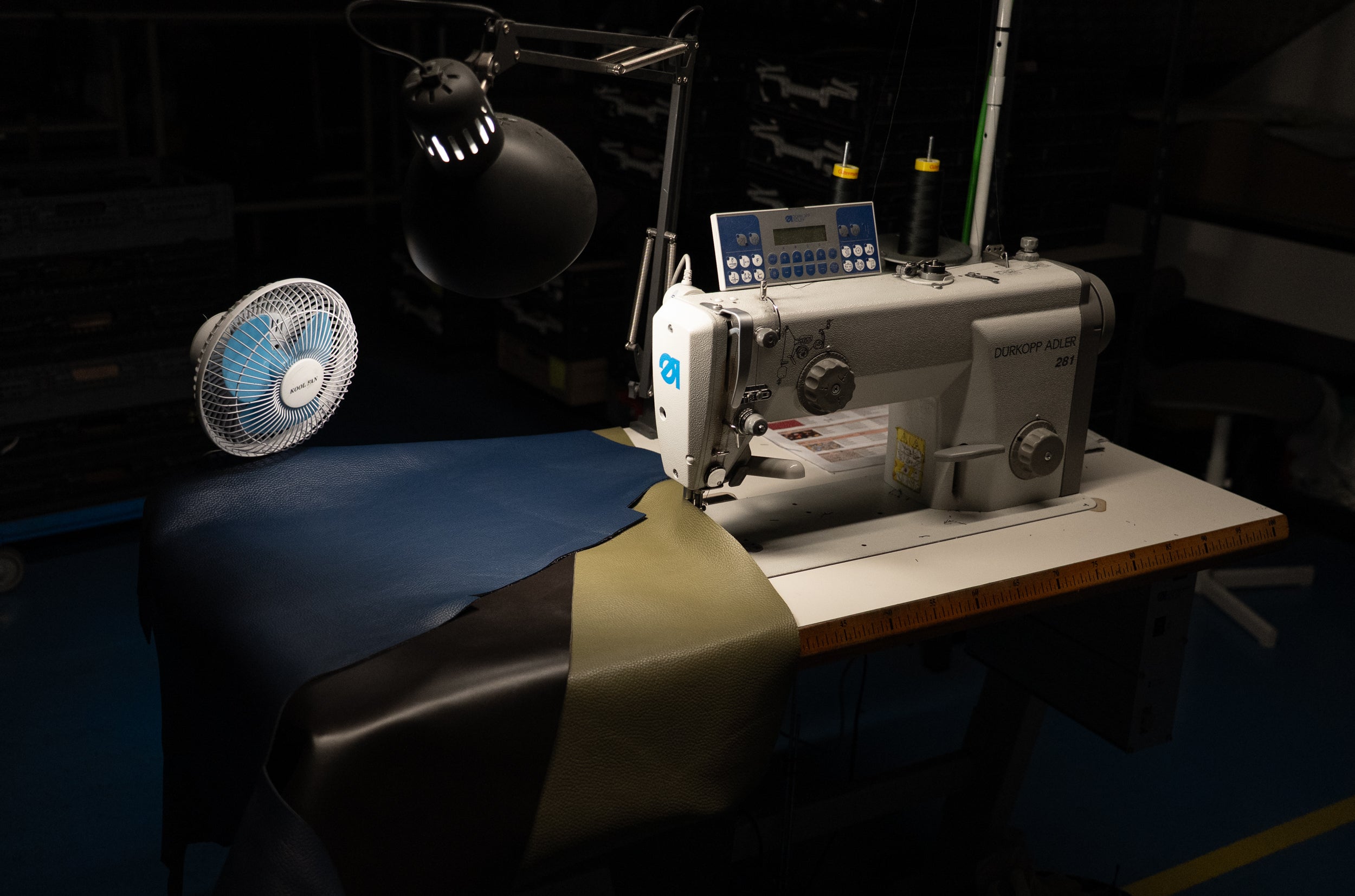 una máquina de coser al lado de cuero de calidad azul ,marrón , negro