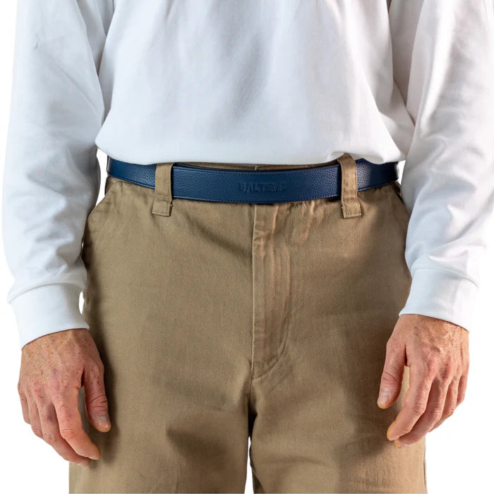 En la foto aparece la cadera de una persona que lleva un cinturon balteus de cuero azul jeans con cierre de velcro sujetando un pantalon marron y una camiseta blanca.