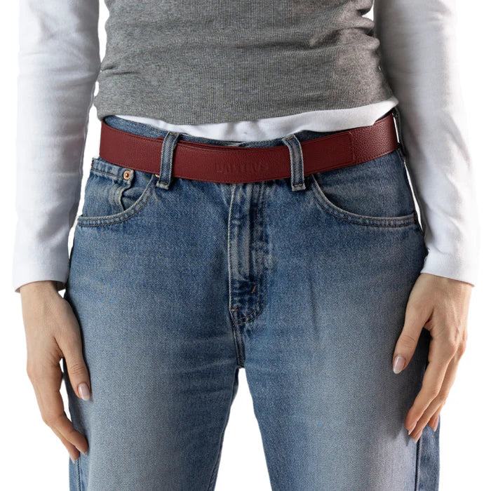 En la foto aparece la cadera de una persona que lleva un cinturon balteus de cuero rojo cereza con cierre de velcro sujetando unos jeans azules y una camiseta blanca.