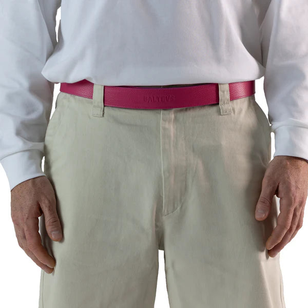 En la foto aparece la cadera de una persona que lleva un cinturon balteus de cuero rosa con cierre de velcro sujetando un pantalon blanco y una camiseta blanca.