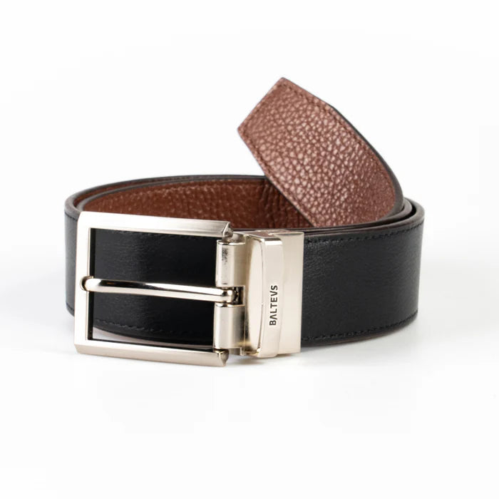 En la foto aparece un cinturon enrollado con hebilla metálica reversible, con cuero de color negro en la parte visible y cuero de color marron en la parte trasera.