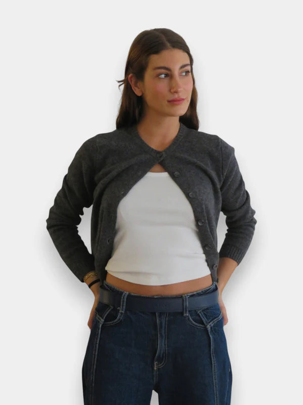 En la foto aparece una chica que lleva un cinturon balteus de cuero azul jeans y con cierre de velcro, sujetando unos tejanos azules, una camiseta blanca y un jersey gris.