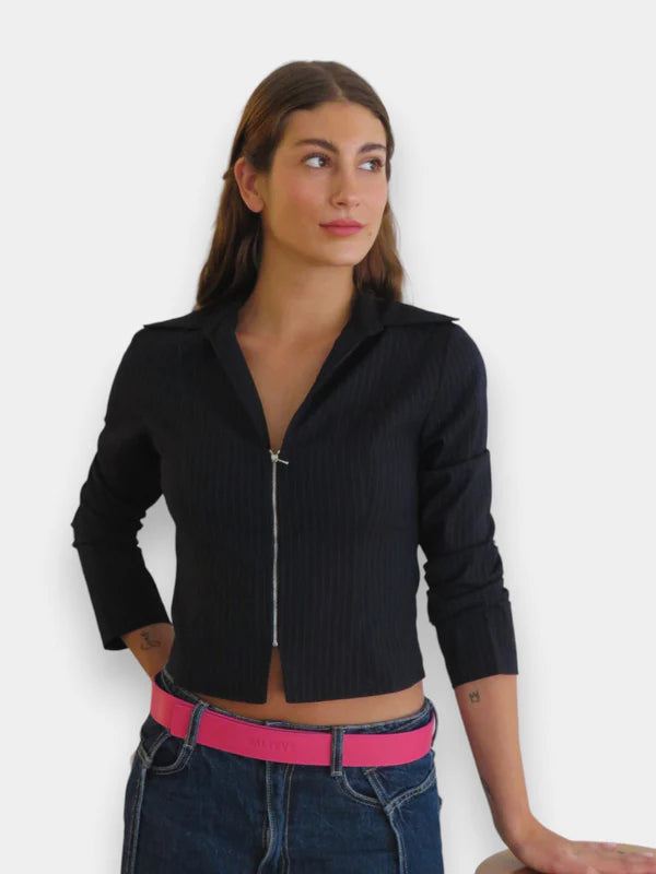 En la foto aparece una chica que lleva un cinturon de cuero rosa y cierre de velcro, sujetando unos jeans y un jersey azul.