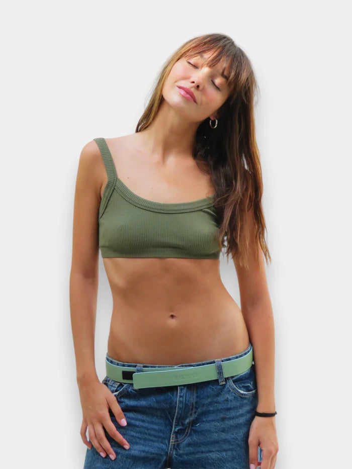 En la foto aparece una chica que lleva un cinturon de cuero verde kiwi y cierre de velcro, sujetando unos jeans y una camiseta verde.